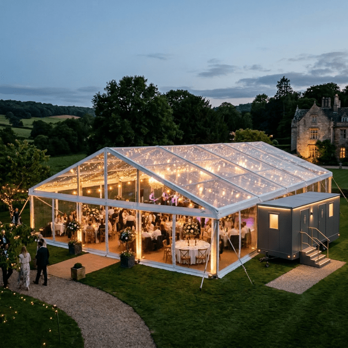 Outdoor wedding reception under clear marquee with string lights and decorated tables